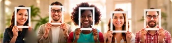 Five smiling people in a row, each holding up a white frame around their face