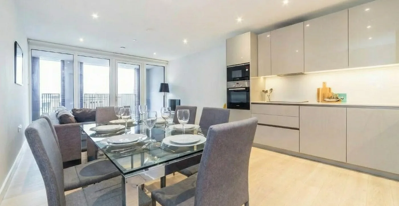 A Marlex kitchen-dining room, the glass table laid for six beside a grey gloss kitchen