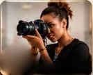 A photographer looking through the viewfinder of her camera