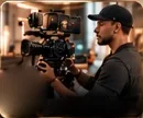 A filmmaker in a black cap shooting with a cinema camera