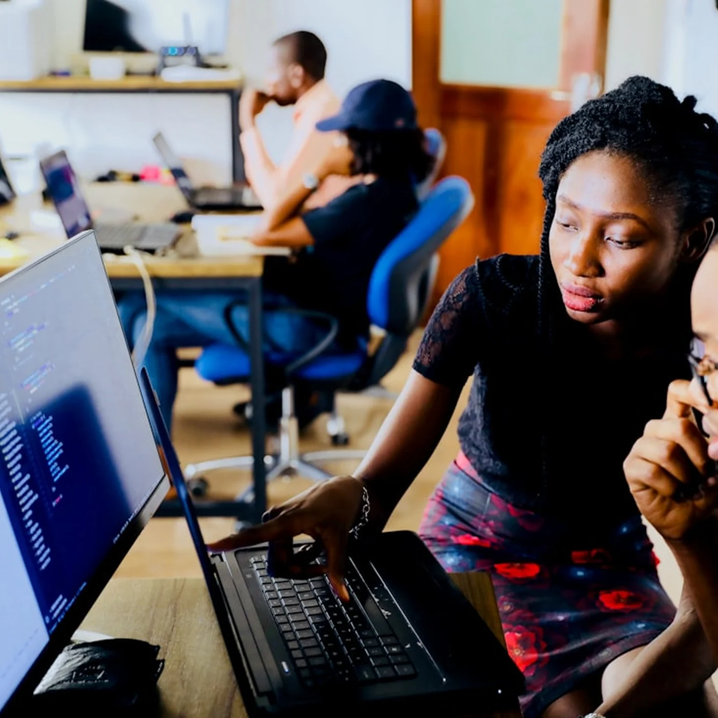 A woman at a laptop showing a colleague something on the screen